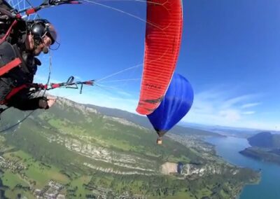 Un parapentiste et la montgolfière Aero-Mountains au-dessus du lac d'Annecy