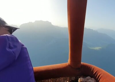 Passager dans la nacelle face aux montagnes au lever du jour