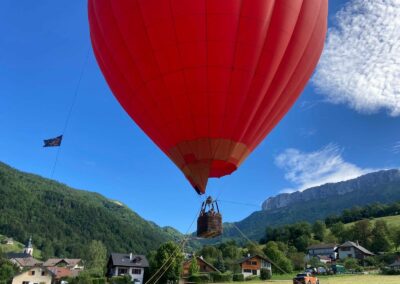 Décollage d'une montgolfière rouge au-dessus d'un village de montagne