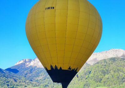 Une montgolfière jaune devant les montagnes